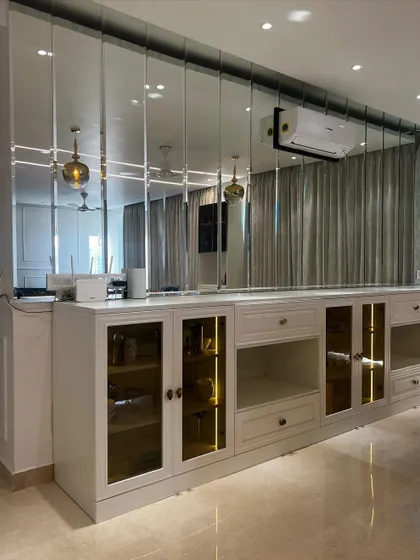 A custom bar and crockery unit designed for a home in Gurgaon. The design features glass doors with internal lighting to showcase glassware, and a mirrored back wall to enhance the sense of space.