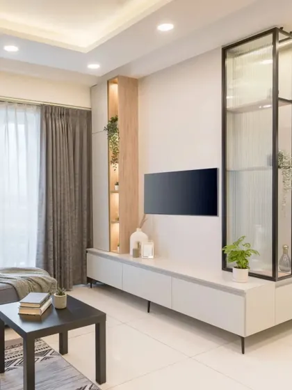 A modern living room with a sleek grey TV unit flanked by two tall display cabinets. One cabinet features fluted glass, adding a touch of sophistication and texture to the minimalist design.