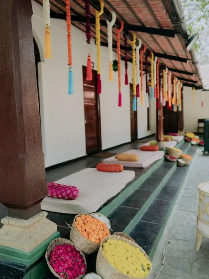 The venue's verandah decorated for the Haldi ceremony with low seating, colorful cushions, and hanging tassels, creating a festive and welcoming space for guests.