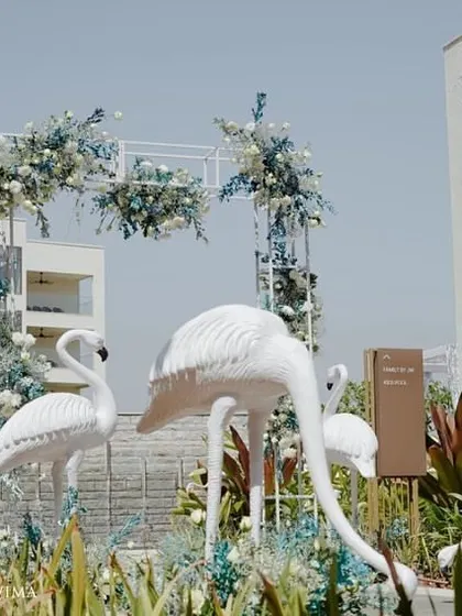 A chic tropical paradise for a brunch pool party. We used elegant white flamingo statues, a floral arch in shades of blue and white, and custom-designed linens to bring the theme to life.