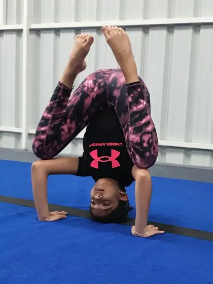 The tripod headstand is a foundational skill for balance and inversion. This student shows a scorpion variation, which also challenges back flexibility.