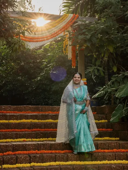 A sun-kissed bride in her beautiful turquoise saree. The natural light and lush green background make for a fresh and vibrant bridal portrait.