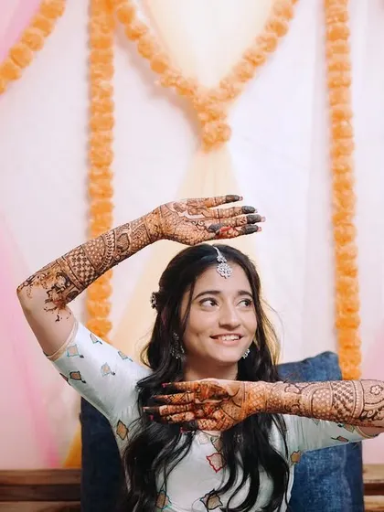 The bride playfully showing off her intricate mehndi design. This shot captures her happy and excited mood during the ceremony.