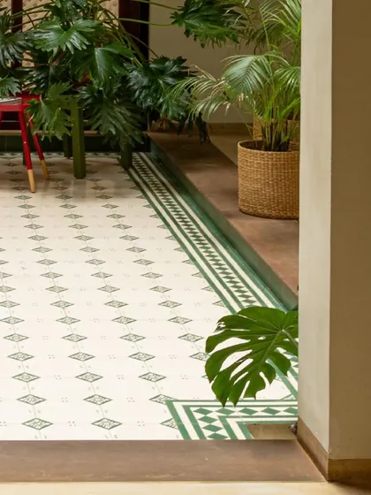 The lush greenery and patterned tile border create a seamless connection between the indoor and outdoor spaces in this courtyard. Every detail is designed to feel natural and harmonious.