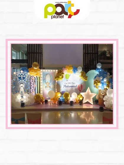 A beautiful stage setup for a hot air balloon themed party, complete with a Ferris wheel prop, marquee lights, and soft, cloud-like decor.