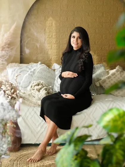 A serene solo portrait of the mother, seated in our cozy studio, taking a quiet moment to connect with her baby.