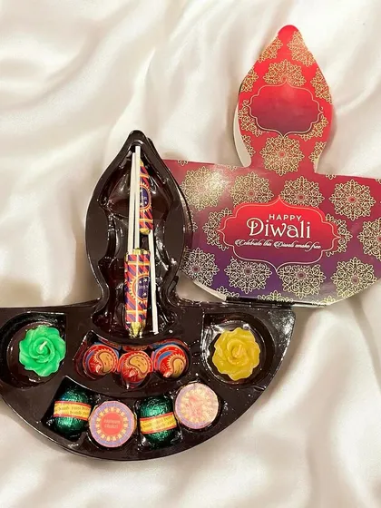 A simple yet elegant Diwali gift box shaped like a traditional diya. It contains an assortment of festive chocolates and a wax candle, making it a delightful and budget-friendly corporate giveaway.