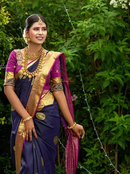A client looking graceful in the navy blue silk saree against a lush green background.