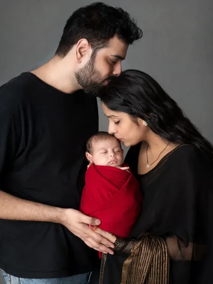 A new family wrapped in love. Parents share a tender kiss on their newborn's head.