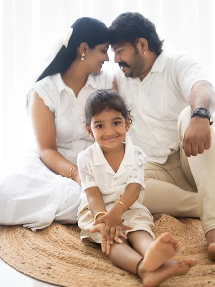 A beautiful family portrait with the parents sharing a loving glance in the background while their daughter smiles at the camera. A perfect mix of posed and candid.