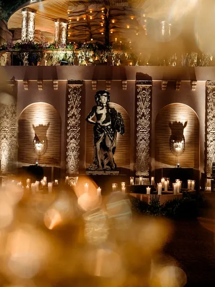 A beautifully framed shot of a Roman statue, seen through the bokeh of foreground lights. This artistic photo captures the magical and dreamlike quality of the event's atmosphere.