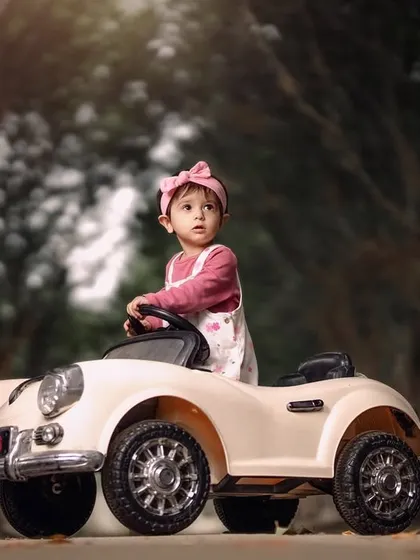 A little girl enjoying an autumn drive in her vintage toy car. The path lined with trees creates a beautiful, scenic backdrop for this portrait.