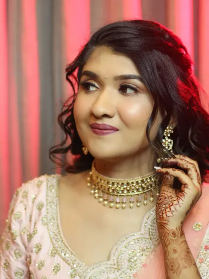 A candid moment showing off her contoured cheekbones and glowing skin. The soft lighting highlights the dimension and radiance of her reception makeup.