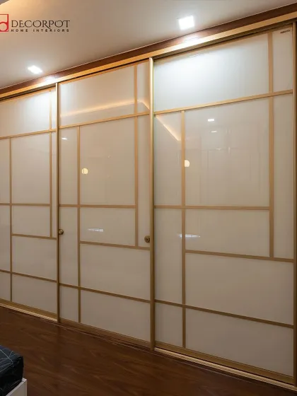 This three-panel sliding wardrobe uses frosted glass with geometric gold-finish inlays. The design is clean and contemporary, adding a touch of understated luxury to the bedroom.