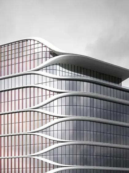 A close-up of the Hilton Kathmandu's facade, showing the interplay between the curved floor plates and the dichroic glass fins that add color and texture.