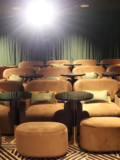 The projector light reflects off the plush, velvety seating, creating a warm and inviting glow in this luxurious, custom-designed space.