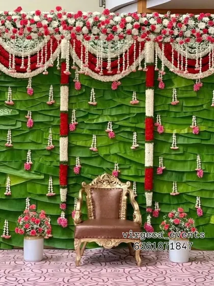 A traditional backdrop for a baby shower, made entirely of fresh green banana leaves and decorated with flower garlands.