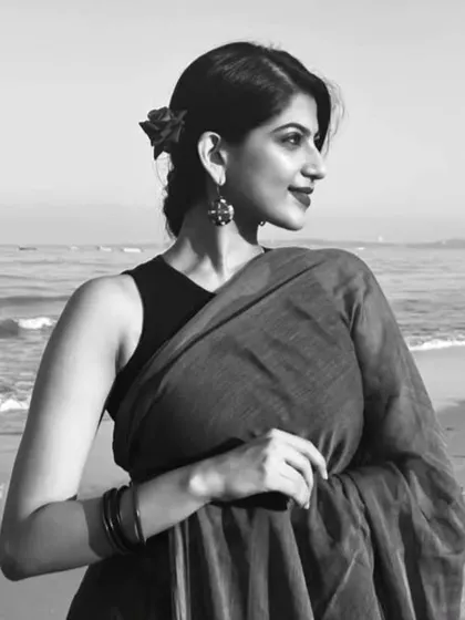 A simple and elegant black and white portrait taken at the beach. Wearing a Suta saree, this image focuses on the silhouette and mood, creating a timeless and artistic feel.