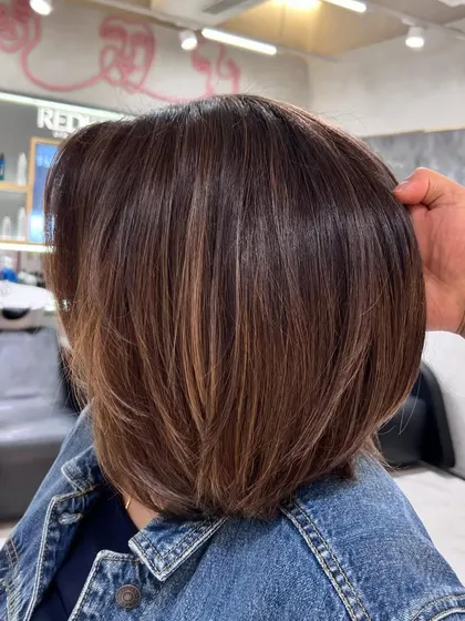 A close-up of the warm brown bob, showing the subtle highlights and the healthy, glossy finish from Redken color.