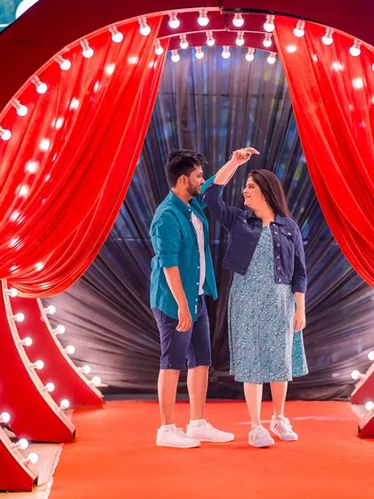 A playful moment on a stage with red curtains. This setup is perfect for couples who want to add a touch of drama and fun to their pre-wedding shoot.