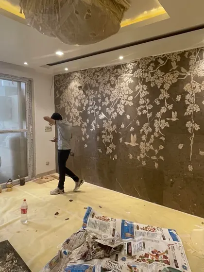 A moment of artistry on site. Here, a craftsman is meticulously installing a custom marble inlay wall mural, a detail that will become the centerpiece of the living room.