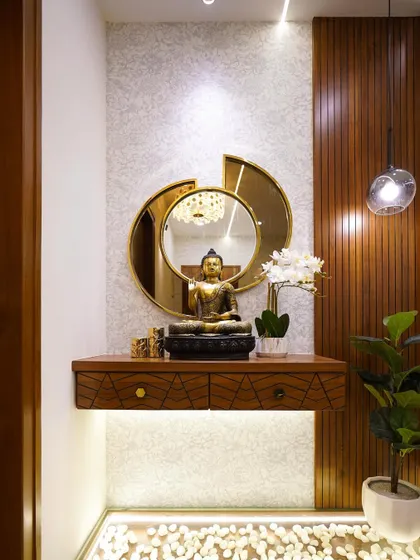 A close-up of a tranquil foyer console. The space features a Buddha statue, a unique gold-framed mirror, and vertical wood paneling, creating a peaceful and welcoming entryway.