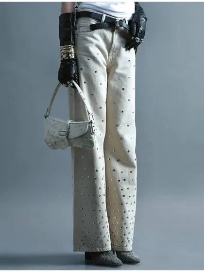 A minimalist, full-body shot focusing on embellished white jeans and a small handbag. This image demonstrates a clean, product-focused approach to fashion photography.