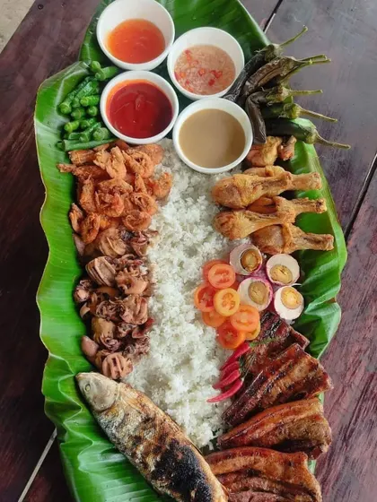 For a truly unique experience, we offer traditional Filipino "Boodle Fight" style catering. A feast of rice, grilled fish, chicken, and sides is laid out on a banana leaf for a communal and fun dining experience.