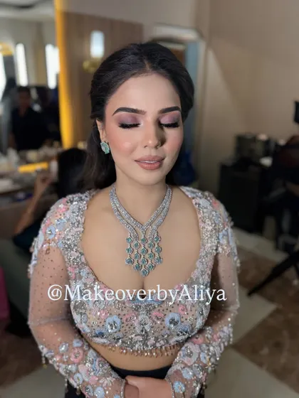 The soft pink tones in the makeup perfectly complement the floral embroidery on her blouse.