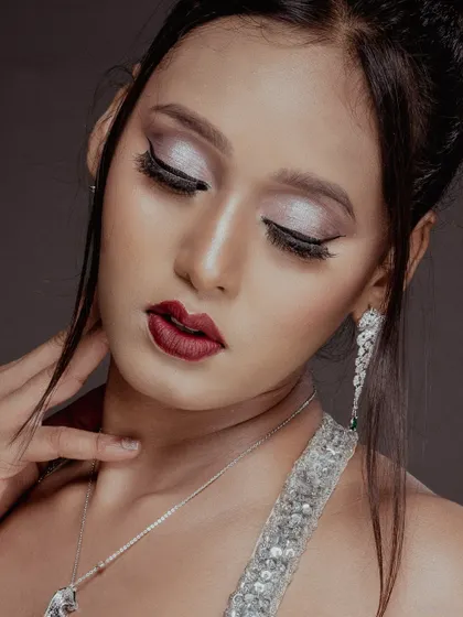 A close-up beauty shot focusing on a glamorous look with silver eyeshadow and deep red lipstick, highlighting the jewellery. This is perfect for both makeup and accessory features.