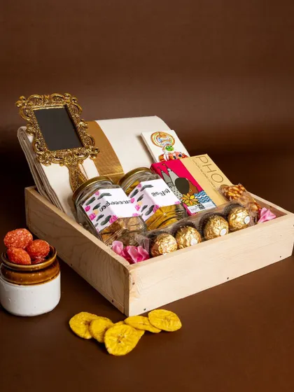 The 'Pichi Poo' hamper, elegantly arranged in a wooden box. This gift combines edible traditions with timeless keepsakes like the kasavu mundu and Aranmula kannadi.