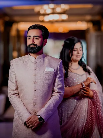 A stylish portrait of the groom, with his bride softly blurred in the background.