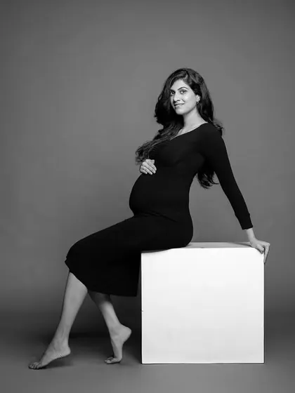 A simple, elegant black and white portrait of the mom-to-be seated, her pose confident and graceful.