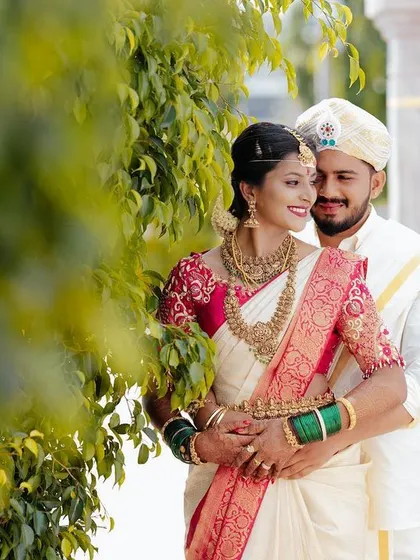 A beautiful portrait of the couple standing among lush green trees, their traditional attire looking stunning in the natural light.