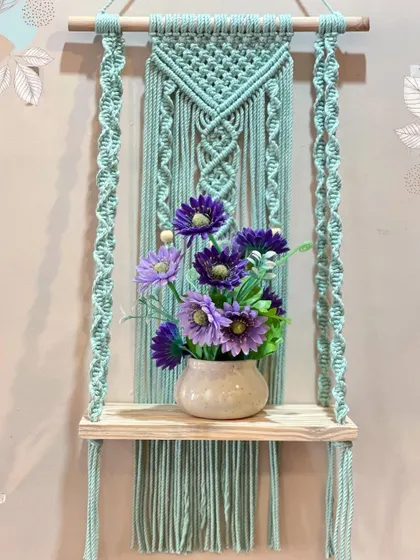 My work is both beautiful and practical. This sturdy macrame wall shelf, shown here with a lovely vase, is perfect for holding small plants, books, or your favorite decorative items.