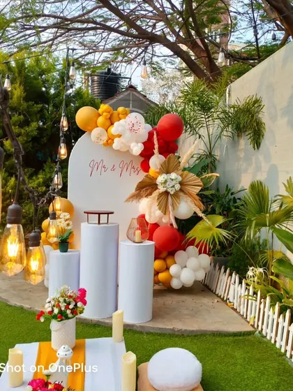 An intimate and stylish anniversary celebration in a garden setting. The "Mr & Mrs" sign, warm-toned balloons, and pampas grass create a chic and romantic vibe.