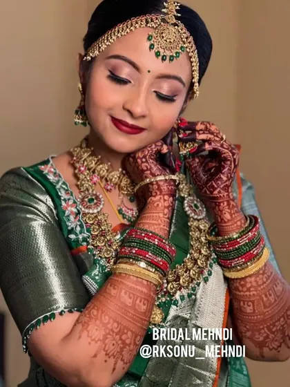A gorgeous shot of the bride, showcasing her beautiful, dark mehndi stain. The rich color of the henna perfectly complements her green silk saree and traditional jewelry.