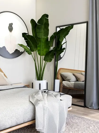 The rattan headboard and large plant bring a natural, calming element to this minimal bedroom. The full-length mirror enhances the sense of space and light.