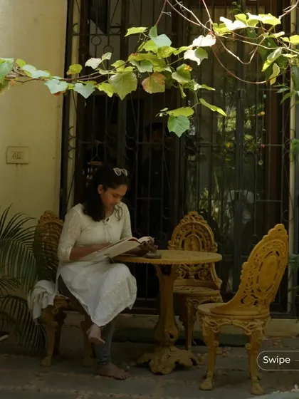 A peaceful outdoor seating area in the garden of the Manjunath Residence, shaded by a vine-covered pergola.