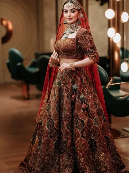 A full-length shot of the bride in a rich, dark lehenga, looking absolutely regal with our jewellery.