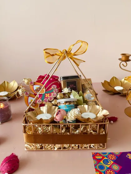 Our luxe metal basket with a pyramid handle is a premium choice for Diwali. It's filled with golden t-light holders, snacks, and decorative hangings.