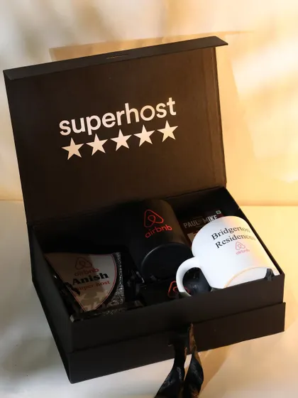 This top-down shot of the open Airbnb hamper highlights the arrangement of each custom item, including two different branded mugs and a personalized award.