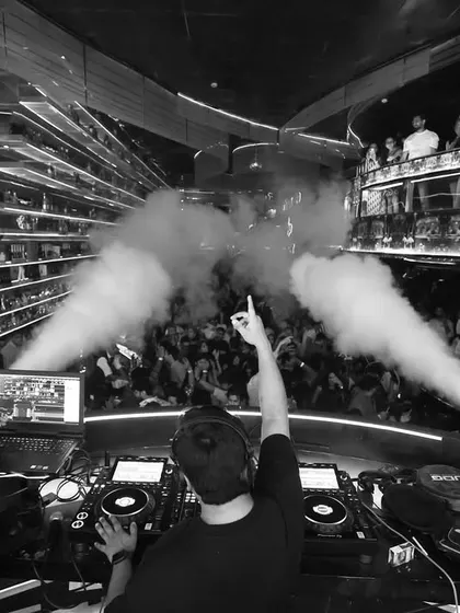 A black and white shot capturing the raw power of a club night. Pointing to the crowd as the CO2 cannons go off, sharing the moment with everyone on the floor.