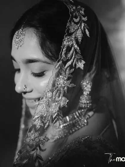 A delicate black and white close-up of the bride. The focus on her embroidered veil and serene expression creates a soft, intimate, and timeless portrait.