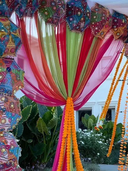 An outdoor entrance arch decorated with colorful drapes and a frame of Rajasthani umbrellas. This welcoming decor piece is perfect for setting a festive tone right from the start.