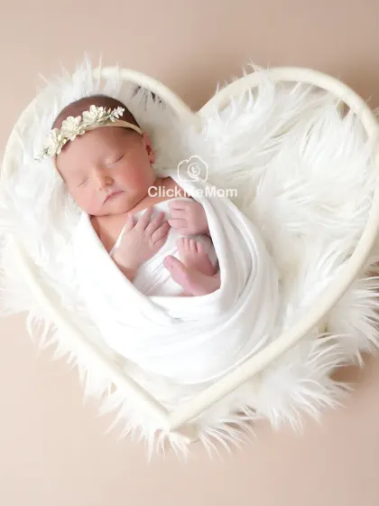 Simple, pure, and angelic. A classic portrait in all white, with your baby nestled safely in a heart-shaped basket, creates a timeless image of innocence you will cherish forever.