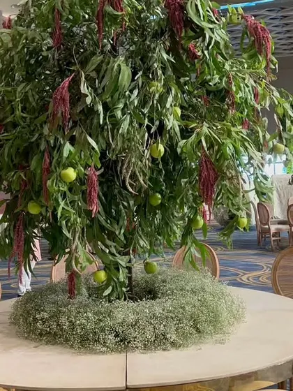 A unique centerpiece featuring a live tree growing from the middle of a guest table, bringing the Italian garden theme to life in an interactive way.