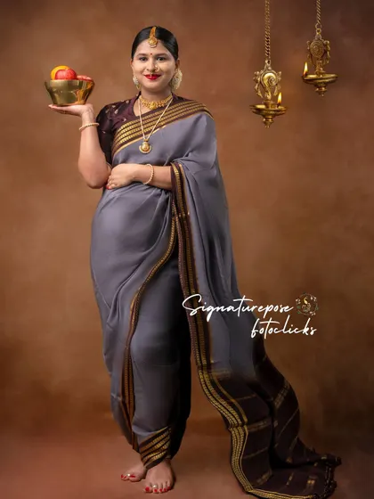 A full-length portrait in a grey saree, with traditional brass lamps adding to the authentic, cultural feel.