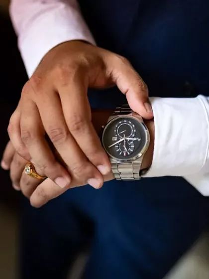 A close-up shot of the groom adjusting his watch, a classic "getting ready" photo symbolizing that it's time.