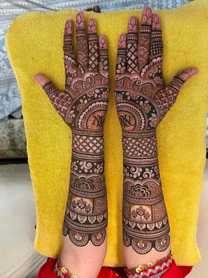 This elegant bridal design features personalized initials 'N' and 'N' in the center of each palm, surrounded by intricate patterns and elephant motifs.
